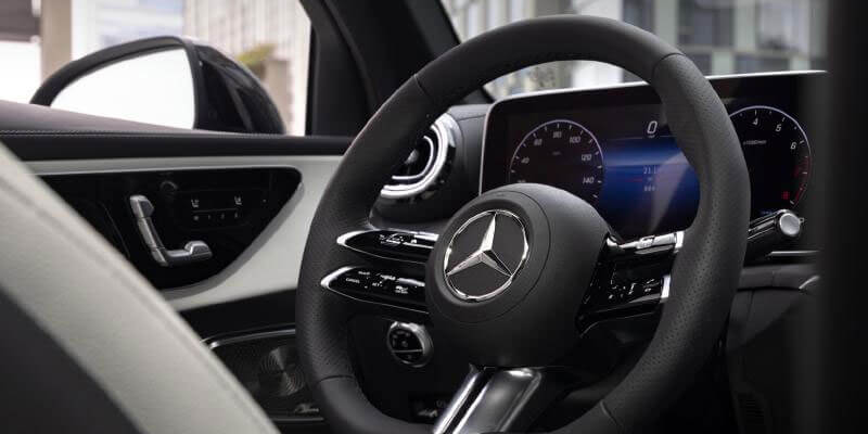 Close-up of a Mercedes-Benz steering wheel and digital instrument display inside the cabin.