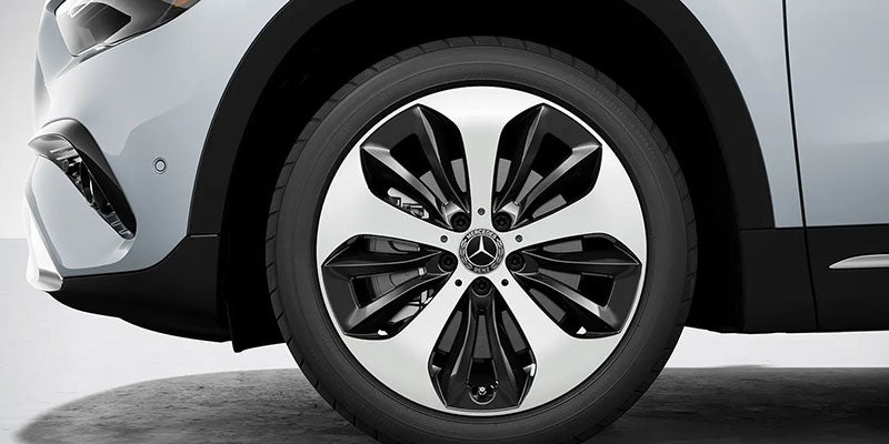 Close-up of a Mercedes-Benz alloy wheel and tire on a white vehicle.